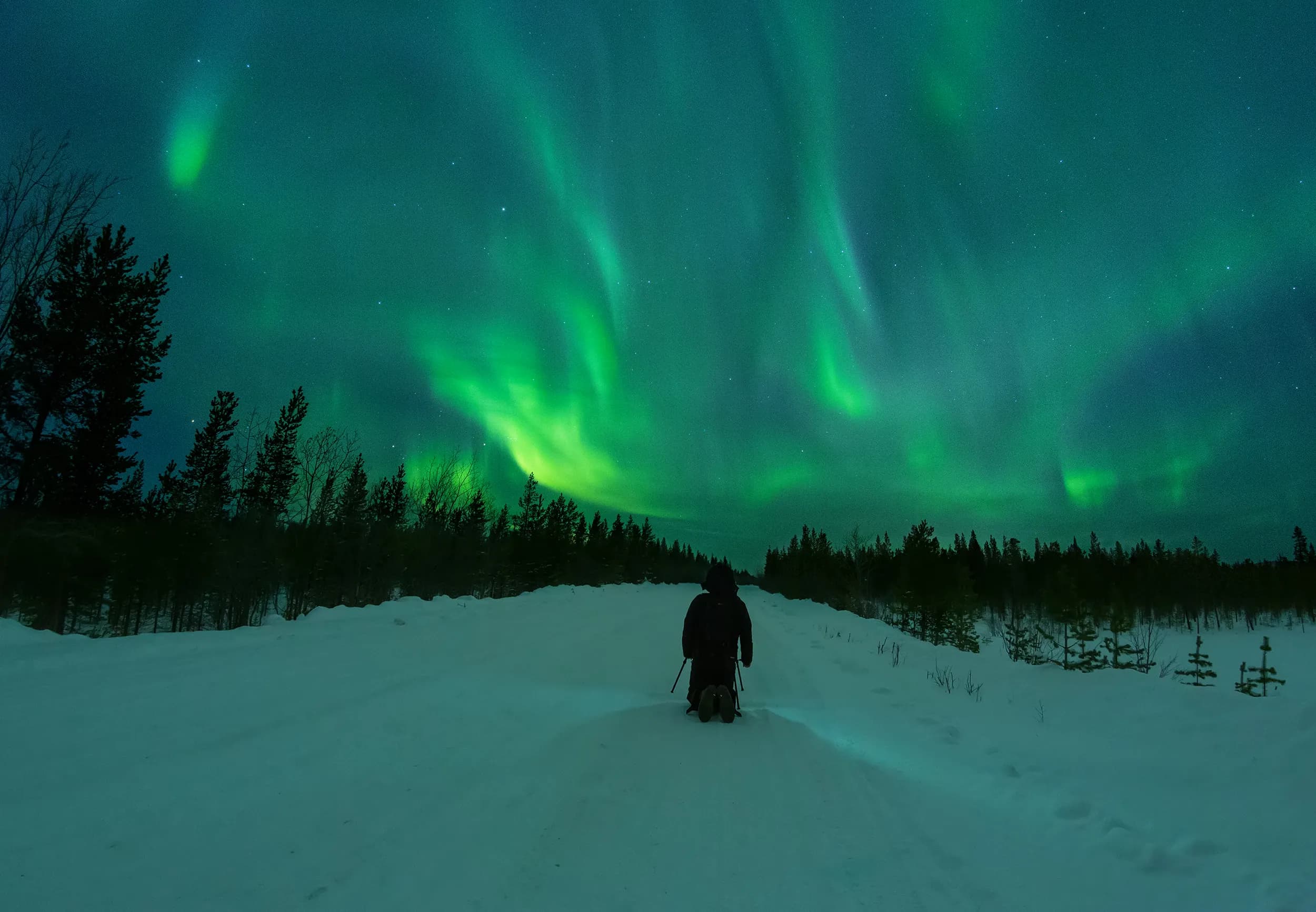 Photographer shooting northern lights in winter landscape