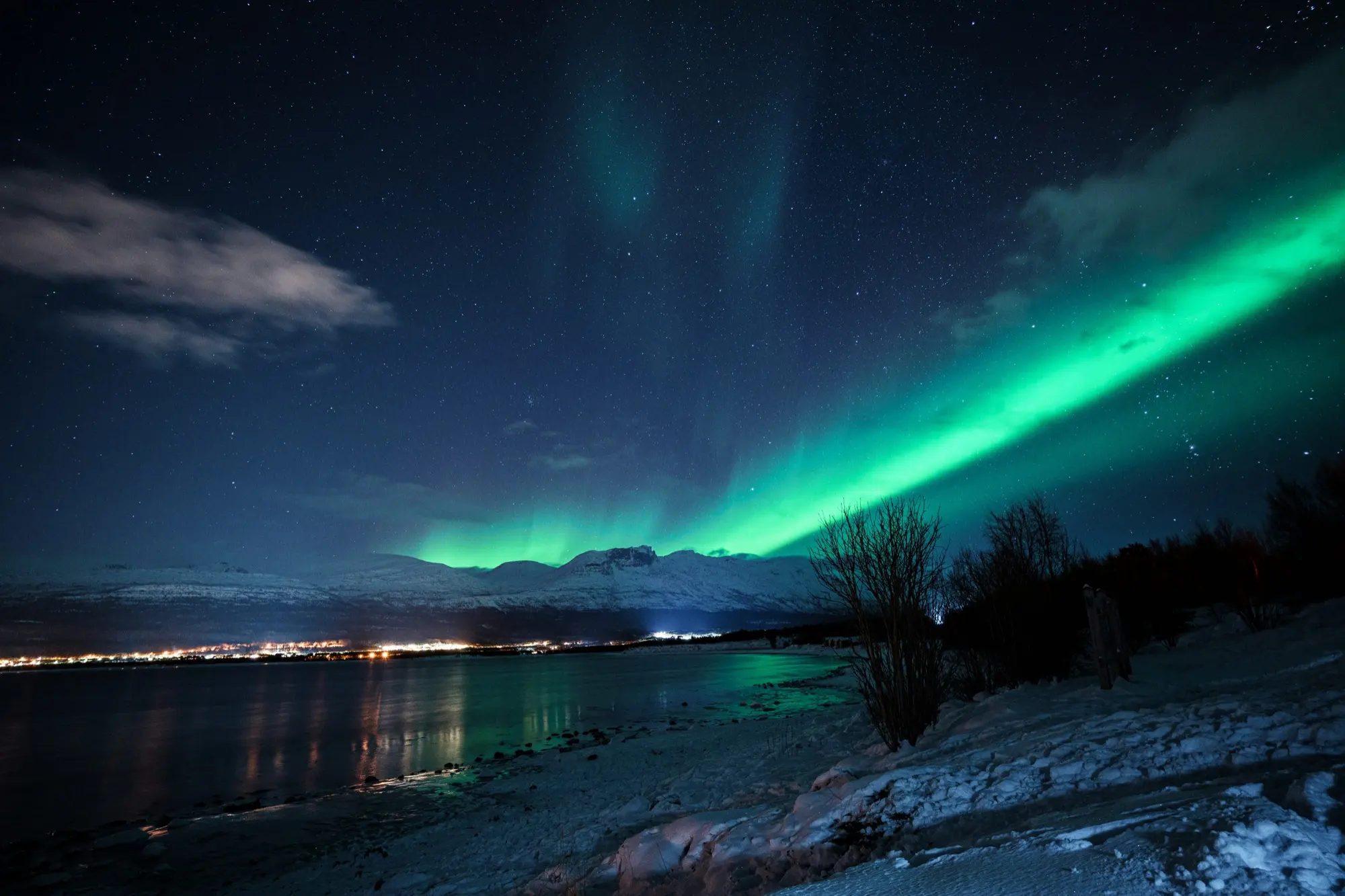 Green aurora over the fjord and city lights of Tromsø